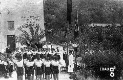 Esponenti del Partito Nazionale Fascista, educatori e bambini della colonia marina "Francesco Marino" mentre eseguono il saluto fascista, dietro al complesso monumentale di  Sant'Antonio. La scritta sul muro recita:" Bisogna vigilare seriamente sui destini della razza dall'infanzia, bisogna curare la razza dalla maternit