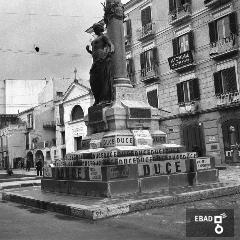 Monumento con statua di dea con scritte inneggianti il duce.
[Il Monumento ai Martiri Politici della Regione Salernitana MCMXI in Corso Garibaldi conosciuto come Statua della Libert opera di Gaetano Chiaromonte. Su indicazione di Anna De Falco]