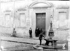 La Scuola Complementare "Giacinto Romano", oggi ingresso della Biblioteca comunale,  e fontana in ghisa lungo l'ala laterale del complesso